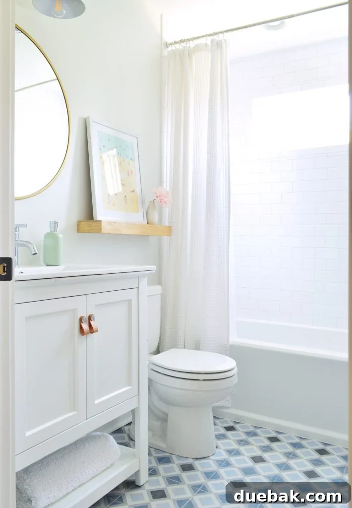 Duplex bathroom with white walls, subway tile shower, and blue patterned tile floor, featuring a basic Delta toilet