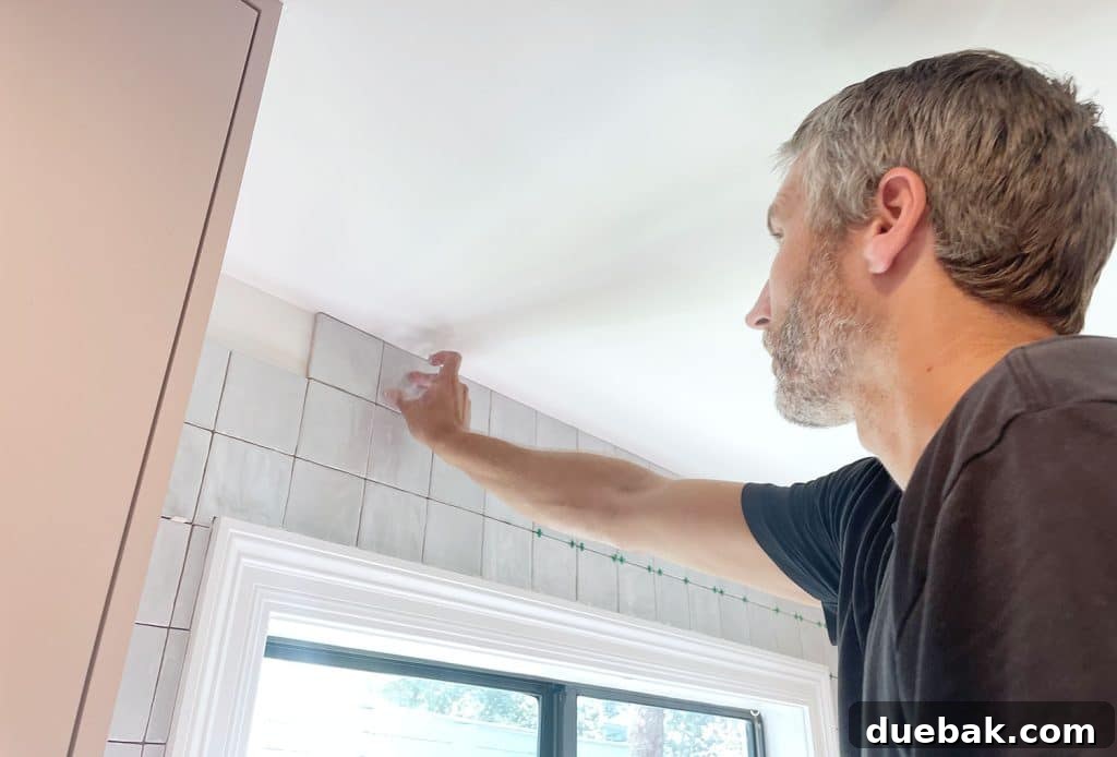 John, the homeowner, adding the final row of tiles above the kitchen window, ensuring a perfect fit.