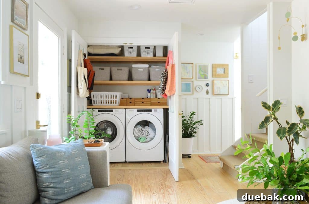 Full view of the open laundry closet behind the seating area, showcasing the stacked washer/dryer and organized storage.