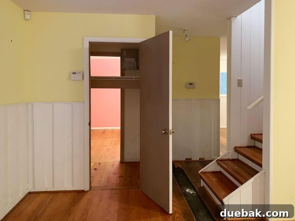 Before photo of the laundry closet with a single door and yellow walls, highlighting its former inefficient design.