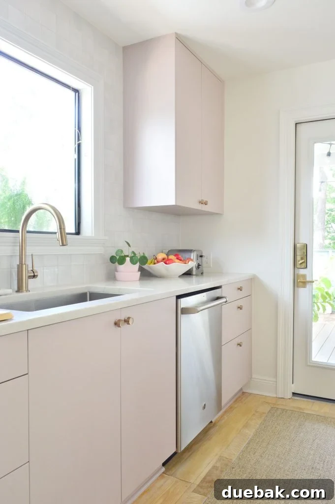 Angled View Of Painted Mauve Pink Kitchen Cabinets With Gray Backsplash
