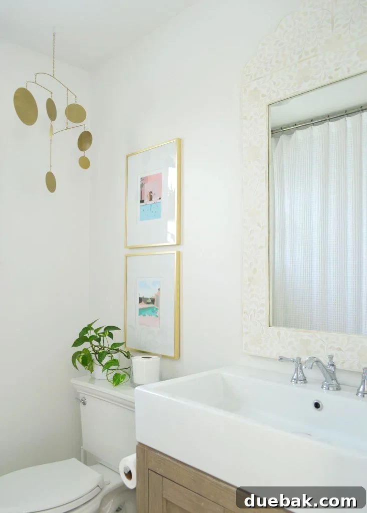 White bathroom with inlay mirror gold picture frames and brass mobile