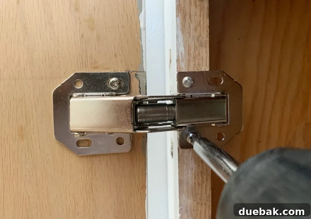 Upgrade Your Old Cabinets with Invisible Hinges 14 Screwing hidden hinge onto cabinet frame in kitchen renovation