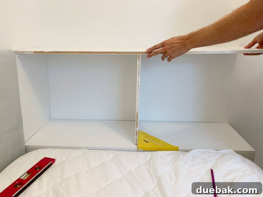 The precise process of fitting the top shelf and middle divider for the custom built-in bookcase at the foot of the boy's bed, illustrating structural planning and integrity.