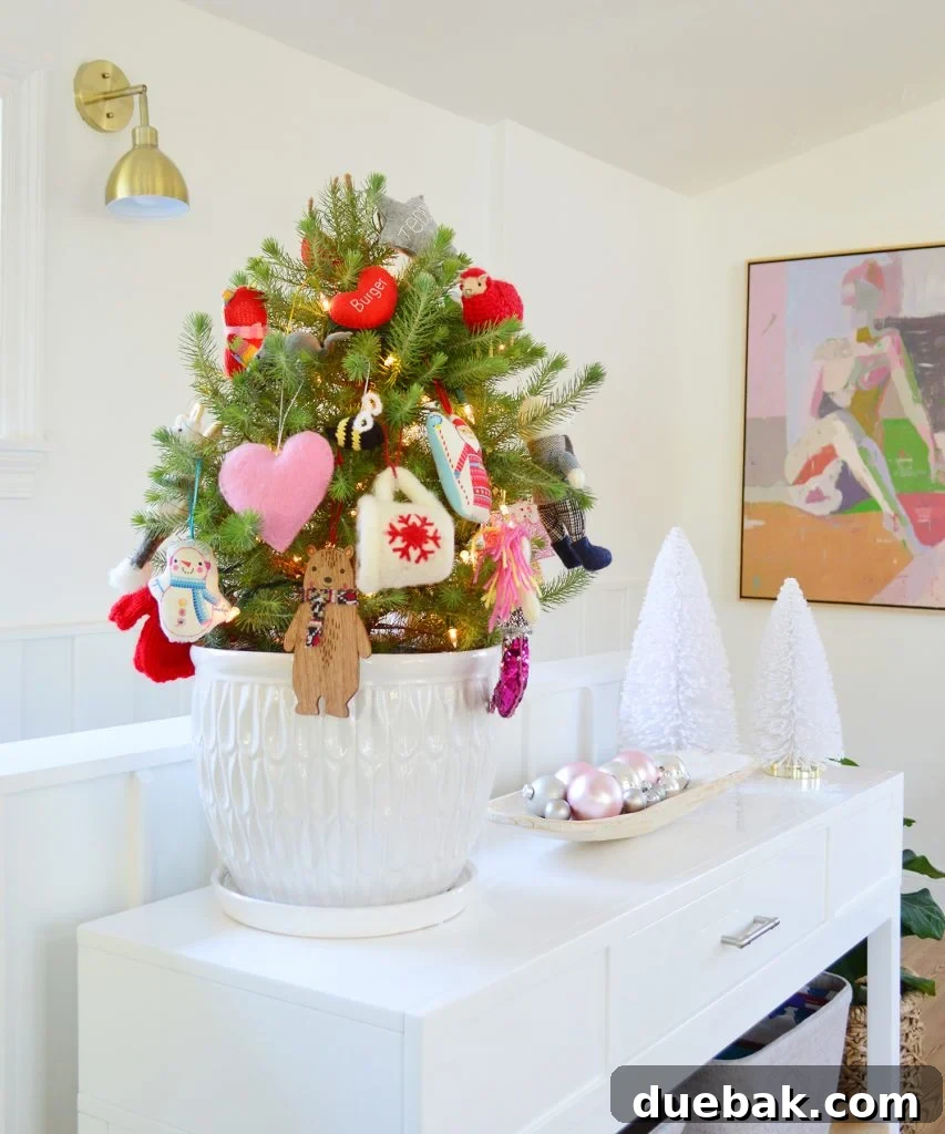 A small tabletop Christmas tree in a white pot, adorned with colorful ornaments, creating a festive and cheerful display.