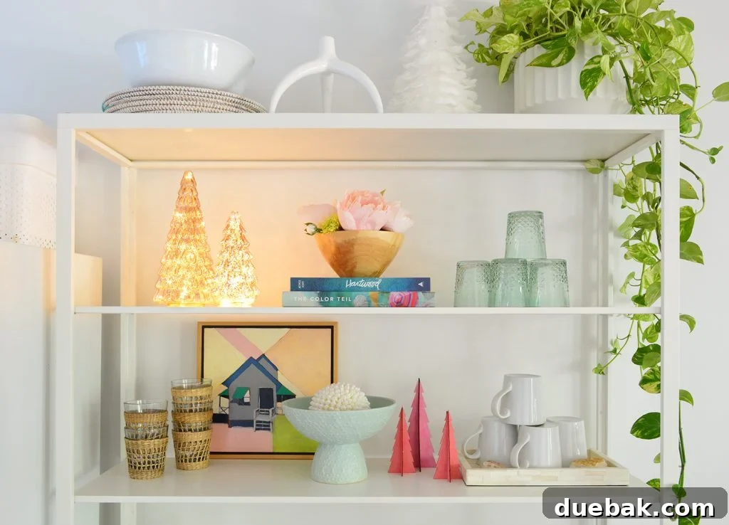 White metal kitchen shelves adorned with a whimsical display of lighted and colorful decorative Christmas trees, creating a vibrant holiday focal point.