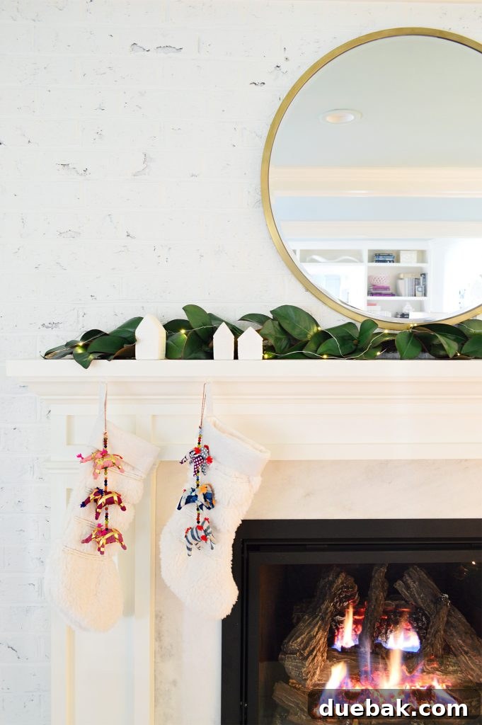 A pristine white fireplace mantle adorned with a lush garland and elegant white stockings, creating a serene and festive holiday display.