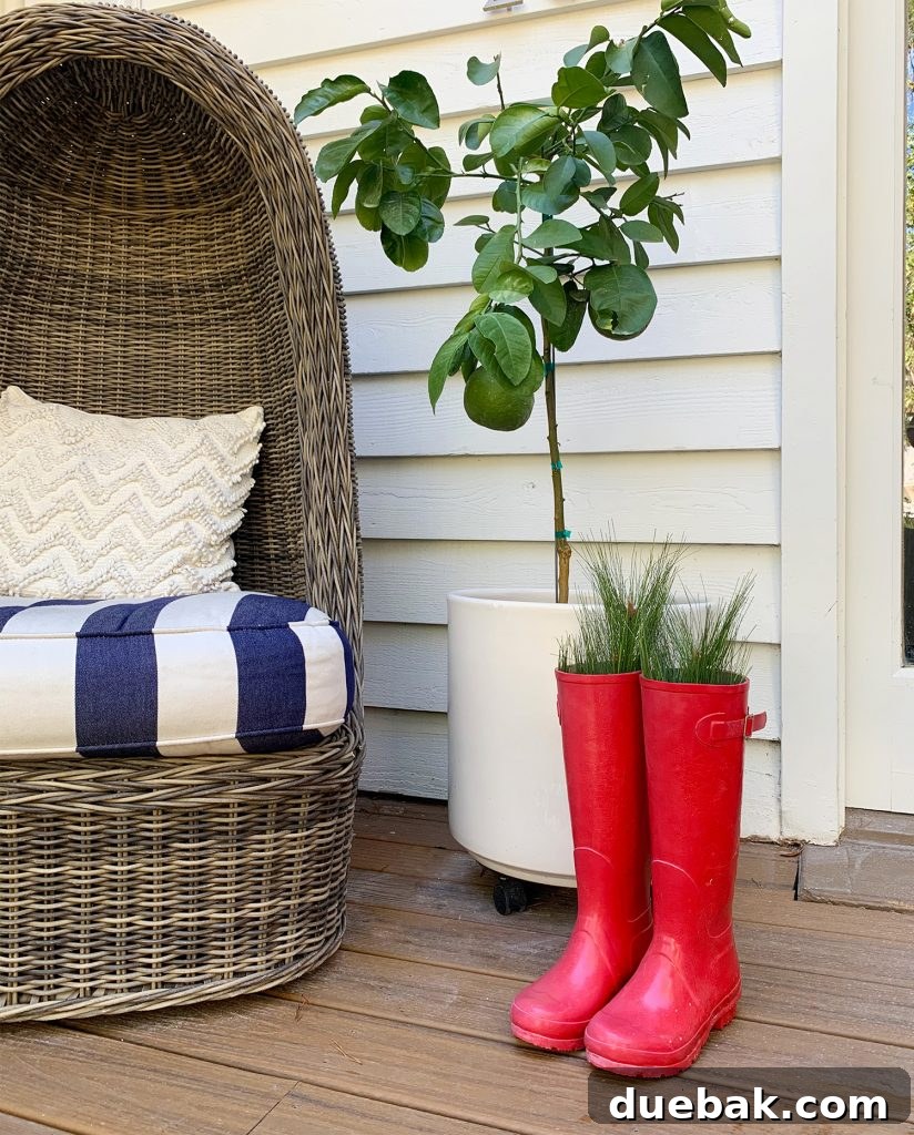 Vibrant red rubber boots adorned with lush faux fir branches, creating a playful and charming holiday display on a festive front porch.