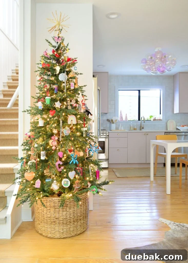 A slender artificial Christmas tree elegantly placed in a kitchen with soft pink cabinets, showcasing how a narrow tree can fit beautifully in various home settings.