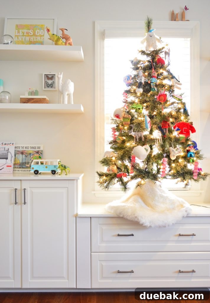 An artificial tabletop Christmas tree adorned with colorful ornaments stands next to kids' toy shelves, creating a festive and playful atmosphere.