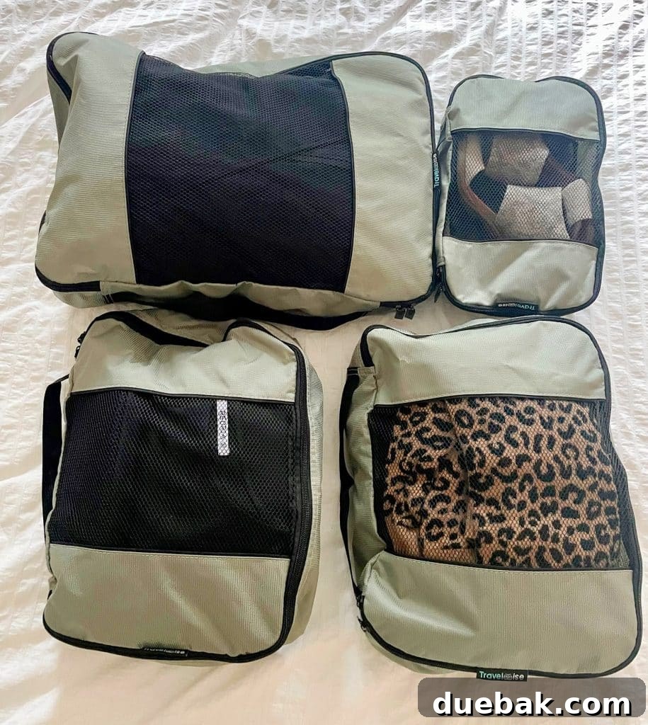 Parisian Chic Packing Secrets 11 Gray zippered packing cubes on bed with minimal outfits for international trip to France