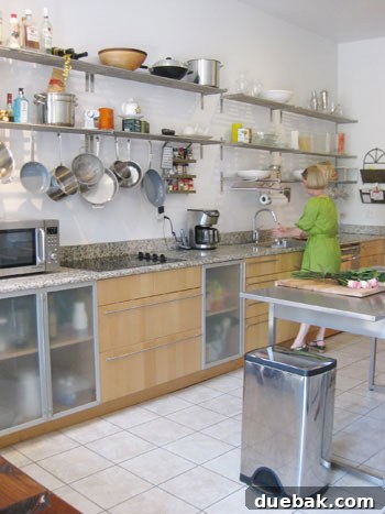 Open House Roulette 8 Modern kitchen with stainless steel open shelving, industrial island, and frosted cabinets