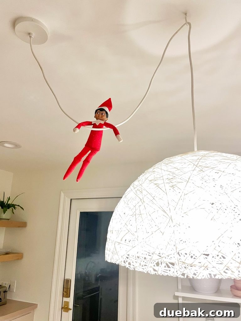 Joyful Simplicity: Our Holiday Edit 8 Elf on the Shelf humorously hanging from a kitchen pendant light cord, bringing holiday fun