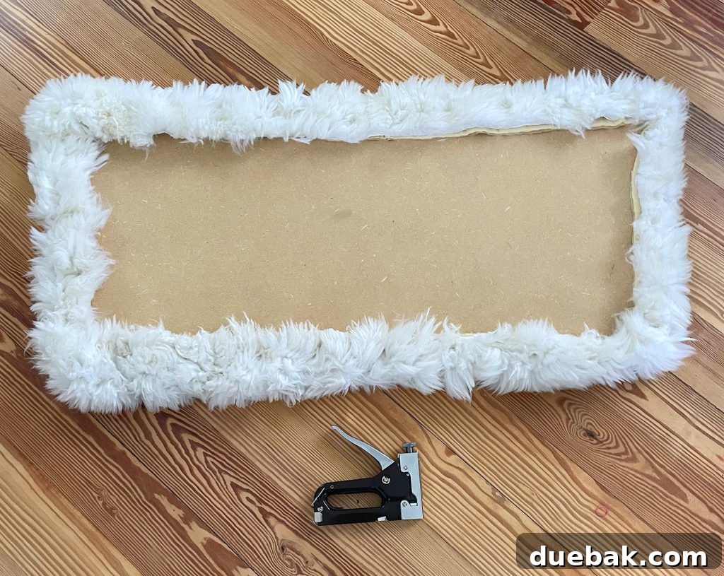 The neatly finished backside of a loveseat seat, now expertly upholstered with a soft sheepskin rug, demonstrating a clean and secure attachment.