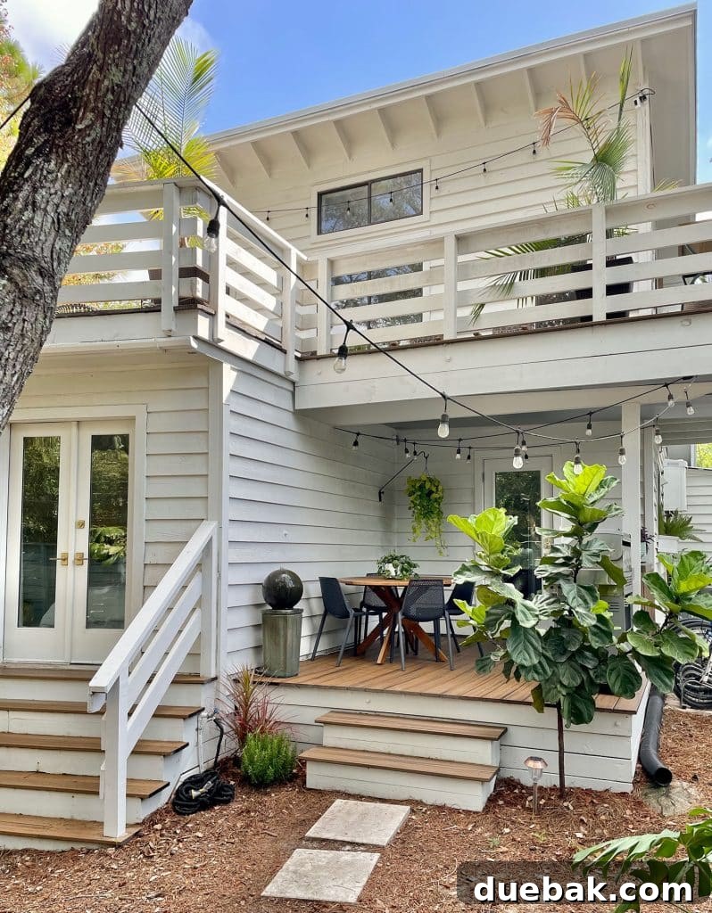 Full View of House With Kitchen Porch On First Floor With Plants And String Lights, showcasing the renewed exterior.