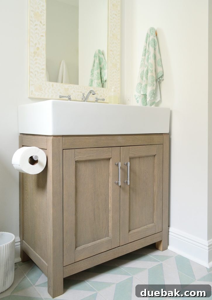 Wood vanity in modern bathroom with mint chevron tile floor