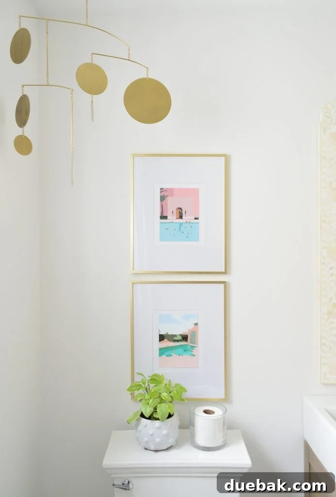 Colorful artwork in gold picture frames above toilet in bright modern bathroom