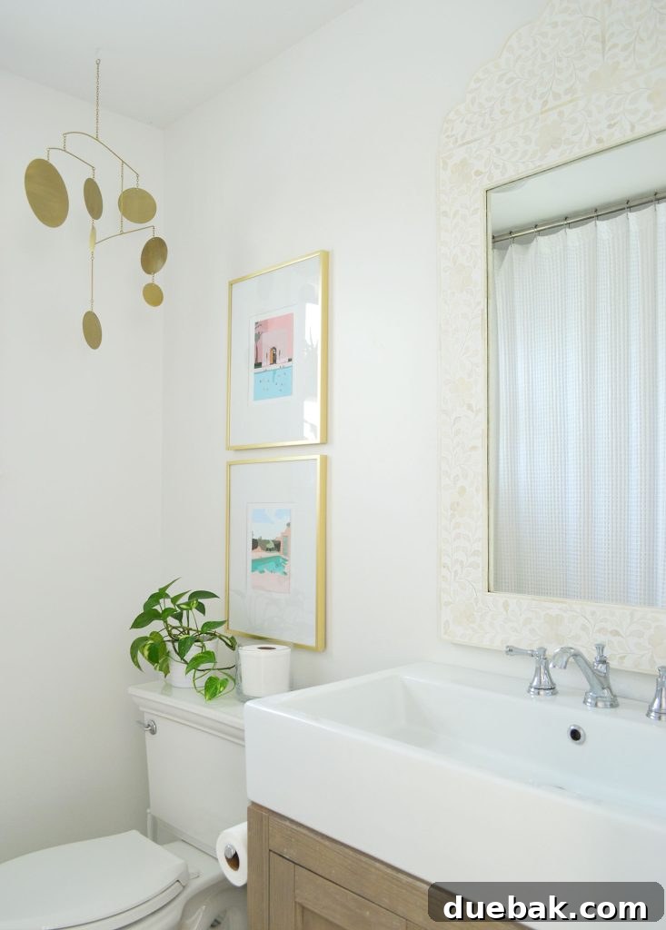White bathroom with inlay mirror gold picture frames and brass mobile