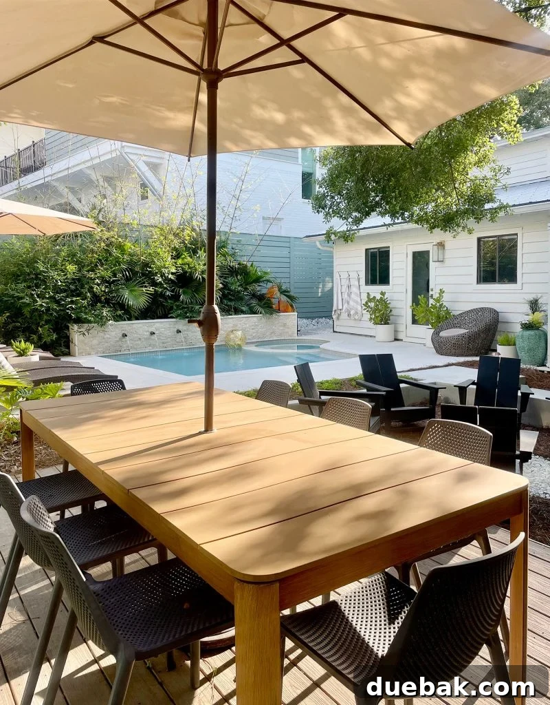 Metal dining table with umbrella in backyard pool area