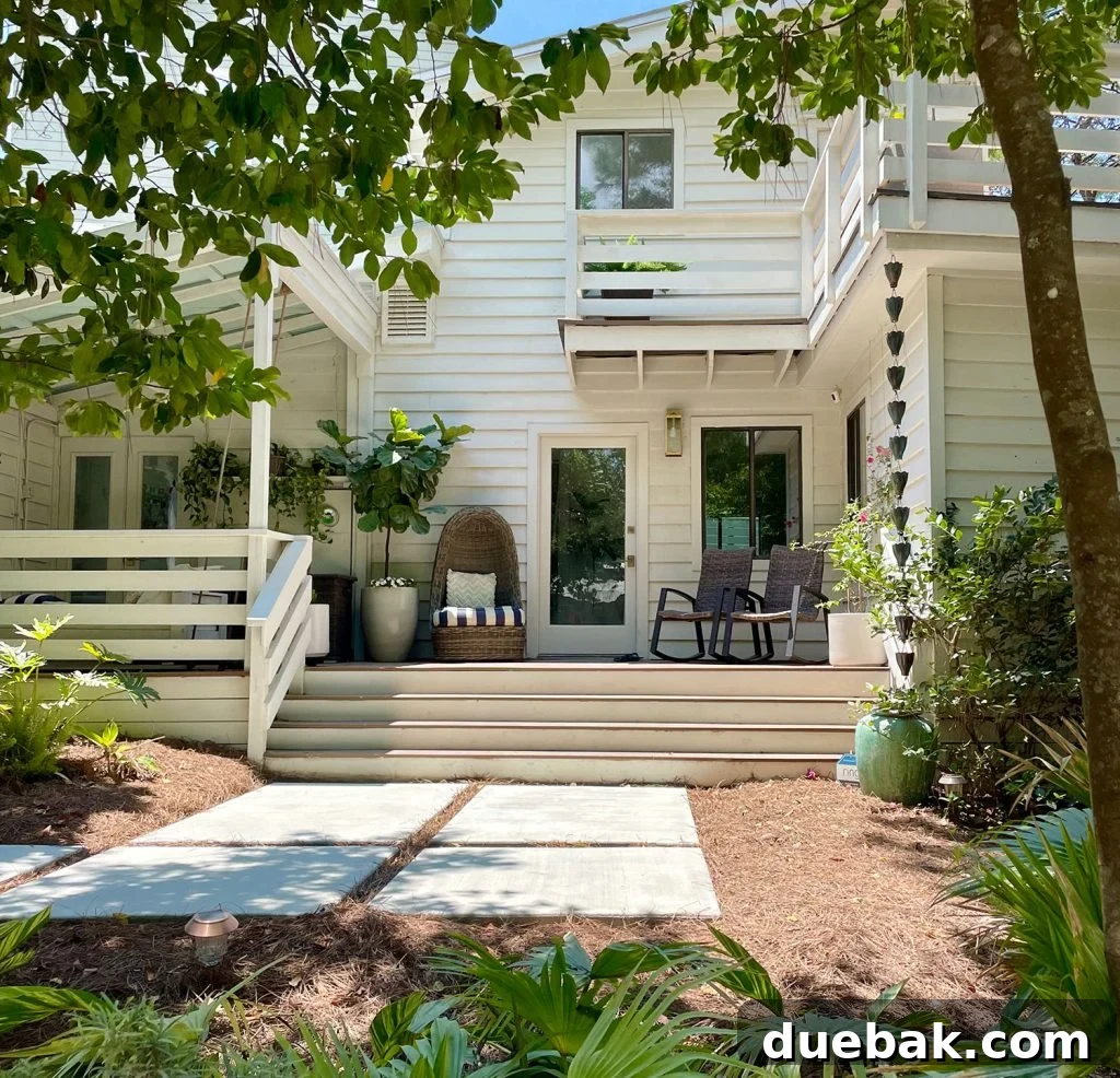 Front Of White Modern House With Lots of Greenery With Large Concrete Walkway