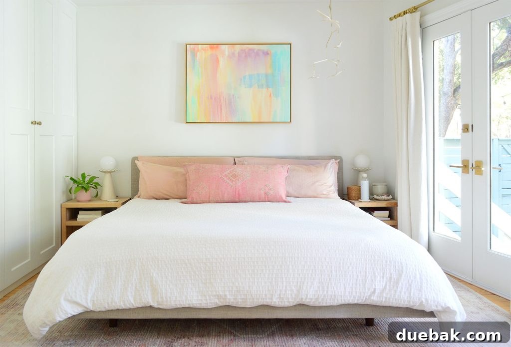 6 Clever Ways We Elevated Our Bedroom 14 Elegant white king bed adorned with soft pink pillows and a vibrant, colorful painting above the headboard