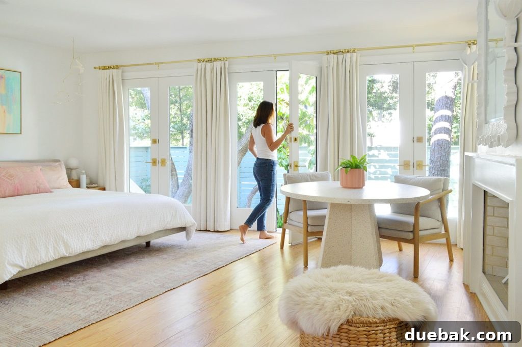 6 Clever Ways We Elevated Our Bedroom 8 Woman gracefully walking through a wall of French doors in a bright, beachy bedroom, showcasing abundant natural light