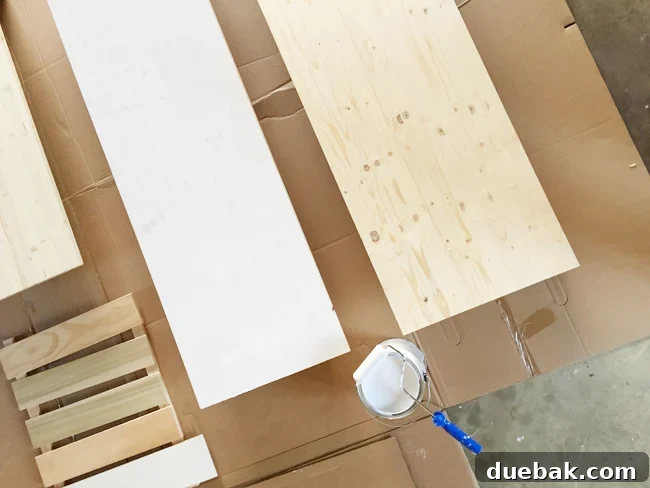 Crafting Custom Built-In Cabinetry 10 Wood project panels from Lowe's being primed and painted white using a small foam roller, preparing them for use as custom countertops for the built-in cabinets