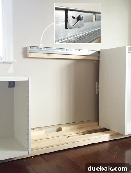 Crafting Custom Built-In Cabinetry 6 Detailed view of an Ikea Sektion cabinet being attached to a metal wall rail using a screw and washer, showcasing the secure installation method