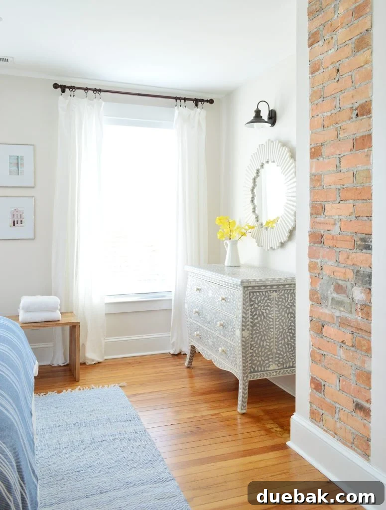 Exposed Brick Fireplace In Beach House Front Bedroom And Inlay Dresser - A cozy space with subtle greige walls.