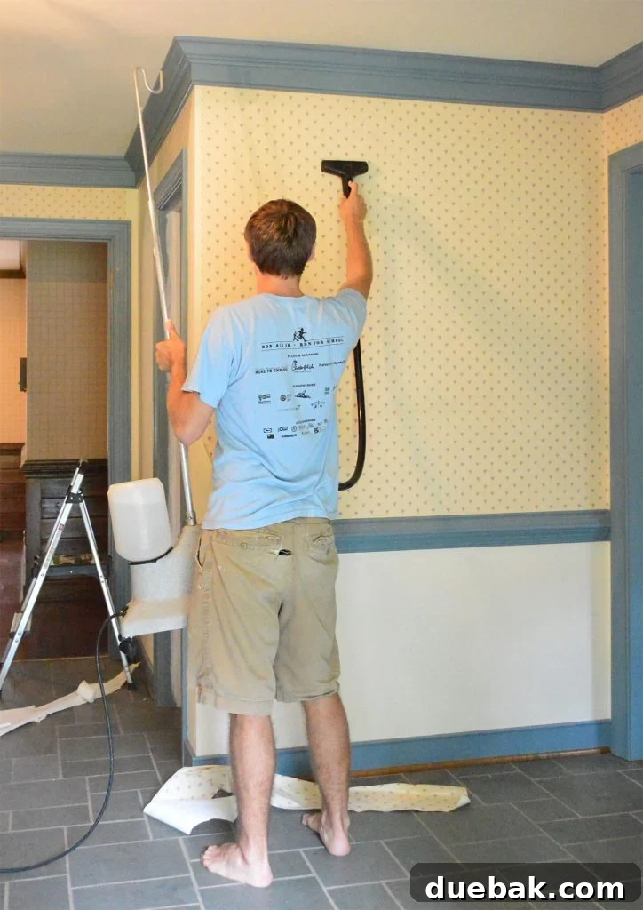 John Using Steamer On Wallpaper In Foyer
