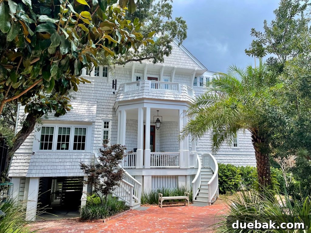 Grand white shingle house surrounded by lush trees, representing traditional luxury