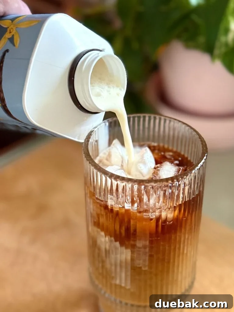 Brew Your Own Perfect Cold Brew 11 Pouring Creamer Into Glass of Iced Cold Brew Coffee Made At Home