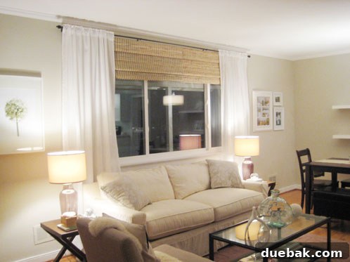 living room with white sheer curtains hung on oil rubbed bronze curtain rod with bamboo roman shades