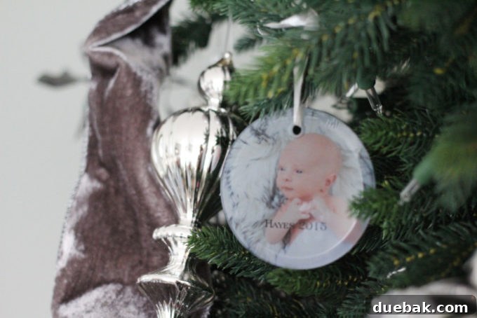 A glass photo ornament from Shutterfly with a baby photo hanging on a Christmas tree.
