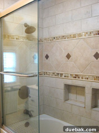 Stunning Richmond Transformation 8 Luxurious upstairs bathroom featuring intricate stone work in the shower, a harmonious blend of neutral tiles, and practical built-in alcoves for toiletries.