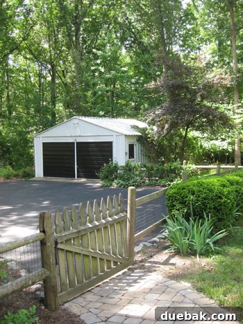Designing Our First Home's Curb Appeal 11 View looking back at the black garage from inside the fenced area on the cobblestone path.