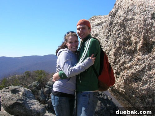 Sherry and John embracing on a mountain after their engagement, looking joyful.