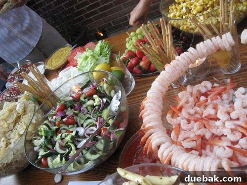 Close-up of a charming wedding food buffet, displaying an assortment of appetizers and main courses presented on elegant serving platters, perfect for an intimate backyard celebration.