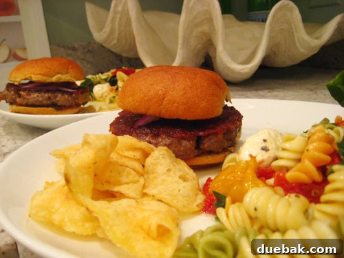 A delicious blue cheese Angus burger with parmesan Caesar dressing, served alongside lemon pepper potato chips and rotini salad, recreating a wedding menu highlight for an anniversary dinner.