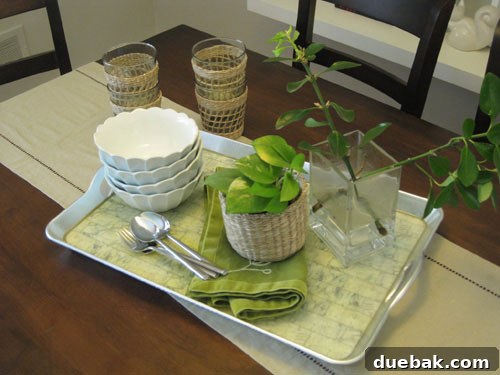The Secret to Straight Candlesticks 3 Dining table before its makeover, featuring a tray with bowls, silverware, a plant, and woven cups