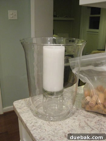 The Secret to Straight Candlesticks 5 A pillar candle elevated on an upside-down juice glass inside a hurricane vase, ready for cork filler
