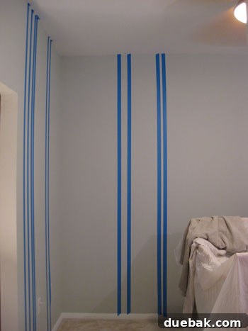 Crafting Your Perfect Nursery 4 Applying painter's tape to the nursery wall for vertical stripes