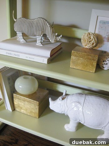 Cardboard Safari Robbie Rhino at Young House Love Cardboard Safari Robbie Rhino, a small white cardboard rhino sculpture, on a shelf next to a ceramic animal, showcasing how DIY decor integrates into home styling.