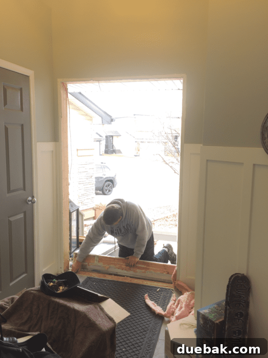 Contractor carefully installing the new front door frame and unit.