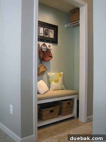Close-up of the mudroom's organizational details, including decorative baskets on the bench, personalized artwork spelling 'MILLER' with photos, and additional hooks for coats.