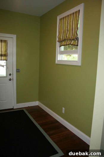 Before image of a green-walled entryway, lacking custom storage or personalized decor.