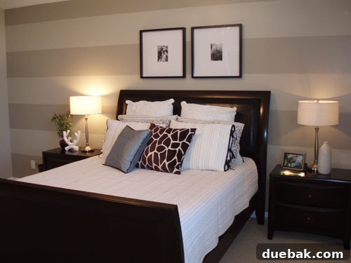 A transformed bedroom with a prominent accent wall featuring elegant, modern stripes.