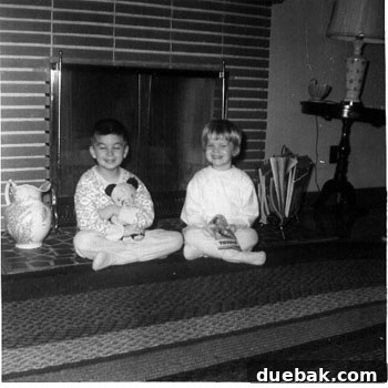 Vintage photo of Lisa and her brother in front of the living room fireplace, a key architectural feature.