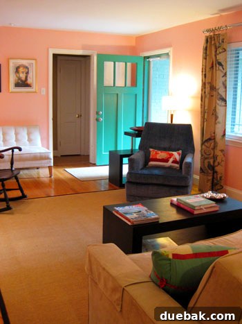 Vibrant pink living room with a striking turquoise front door, showcasing modern design, bold colors, and an inviting atmosphere in a mid-century home