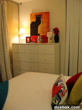Decorated corner of the bedroom, showing a dresser with leaning art, and colorful accessories.